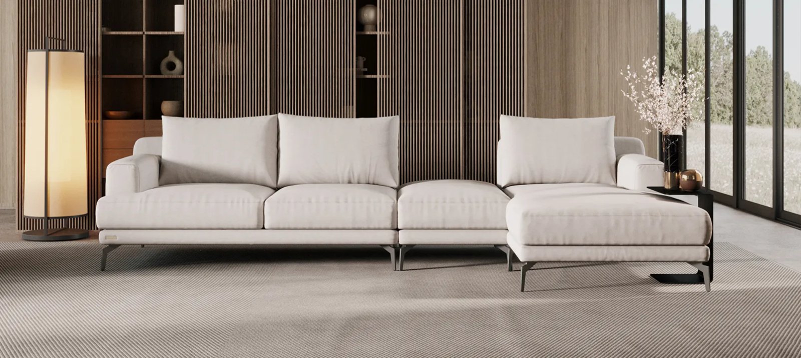 Pilka Sydney sofa moderniame interjere su minkštomis pagalvėmis ir plačiais porankiais.