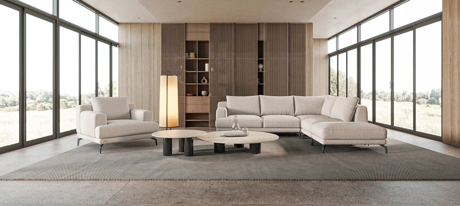 Pilka Sydney sofa iš priekio su plačiais porankiais ir minkštomis nugaros pagalvėmis.