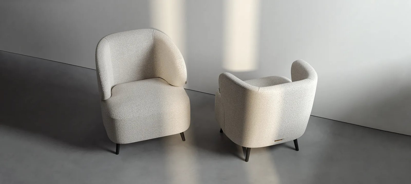 Noto fotelis kampu su minkšta sėdyne ir apgaubiančiu atlošu šiltame moderniame interjere.