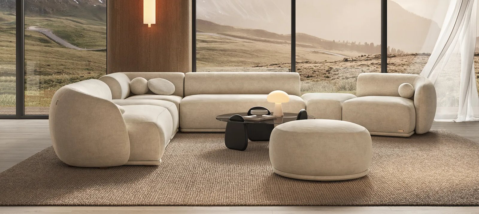 Kreminė Otis modulinė sofa su lenktais kraštais ir apvaliomis pagalvėlėmis. Priekyje didelis minkštas pufas.
