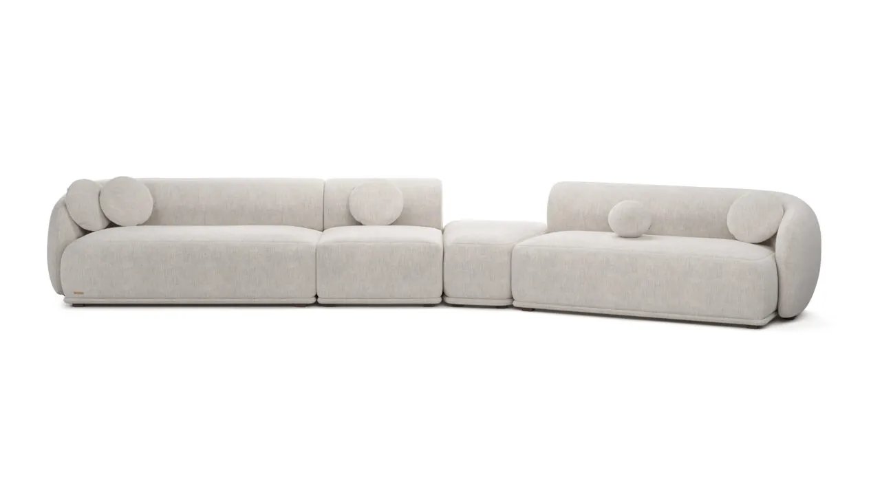 Ilga kreminė Otis modulinė sofa iš kelių žemų dalių su lenktais kraštais ir apvaliomis pagalvėlėmis.