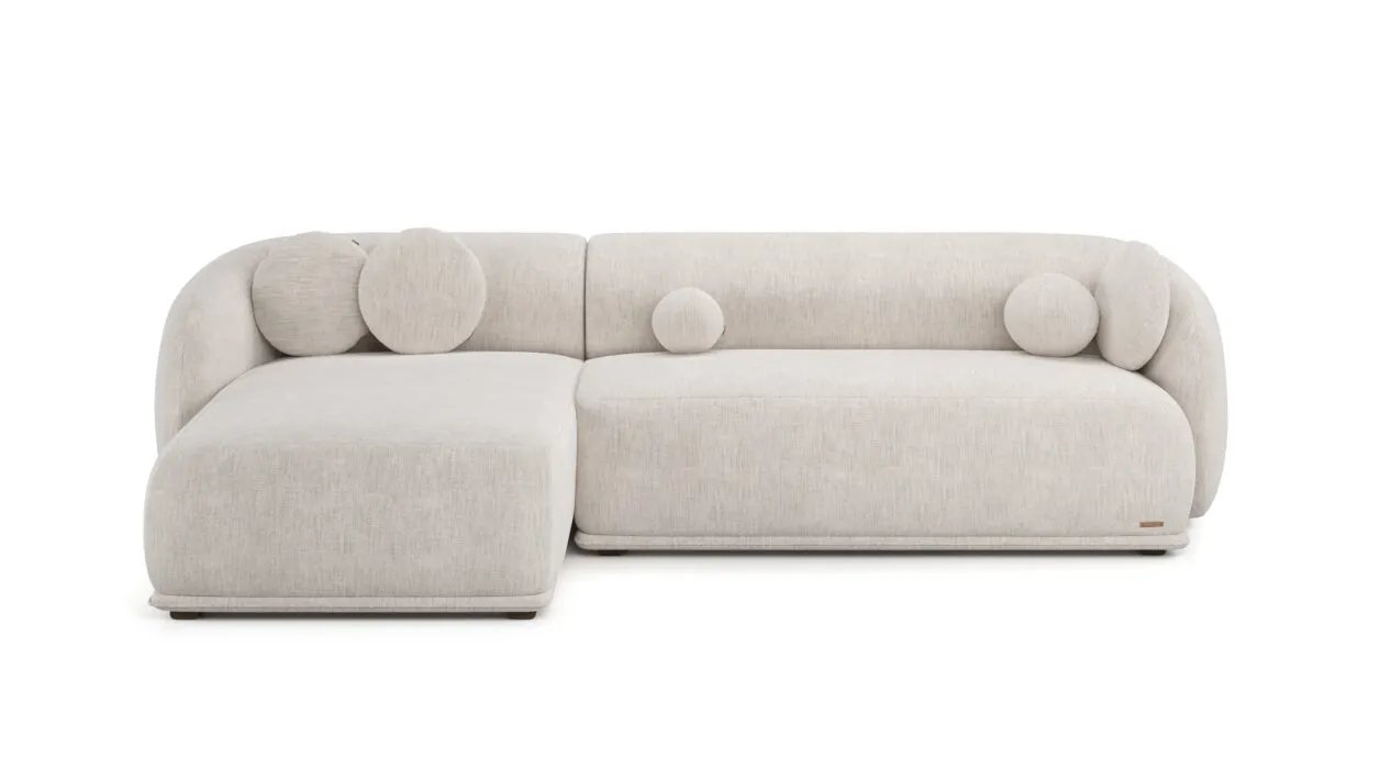 Kreminė Otis kampinė sofa iš priekio su plačia gulimąja dalimi ir trimis apvaliomis pagalvėlėmis.