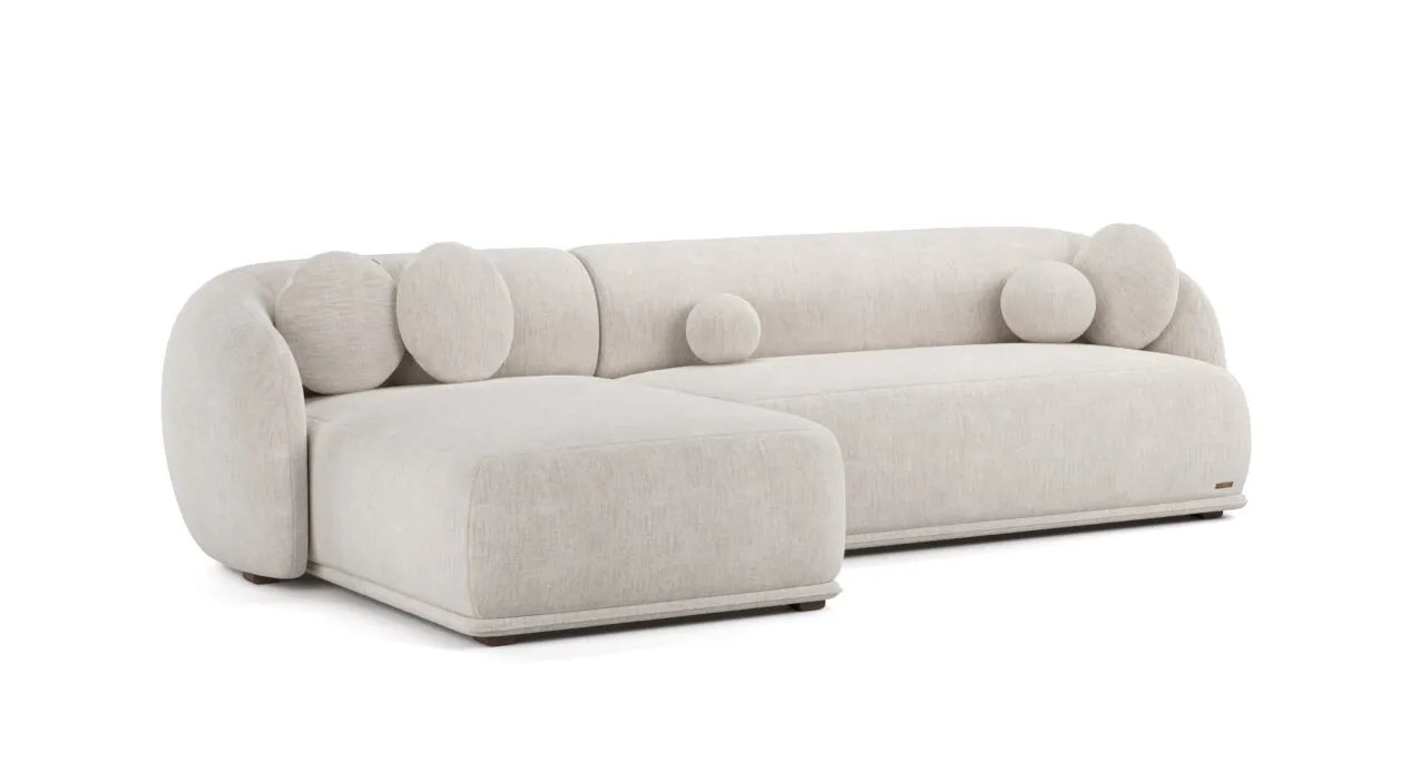Kreminė Otis kampinė sofa su ilga kairine gulimąja dalimi ir apvaliomis dekoratyvinėmis pagalvėlėmis.