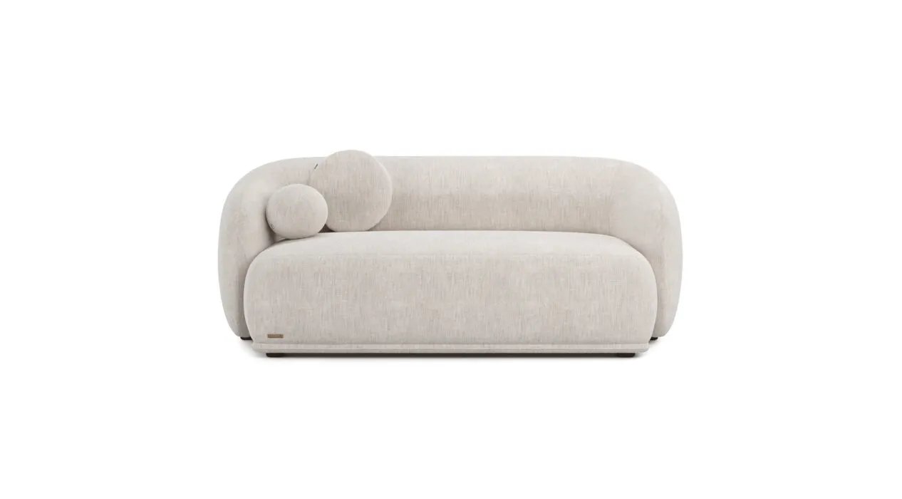 Kreminė Otis sofa iš priekio su plačia vientisa sėdyne ir dviem apvaliomis pagalvėlėmis kairėje.