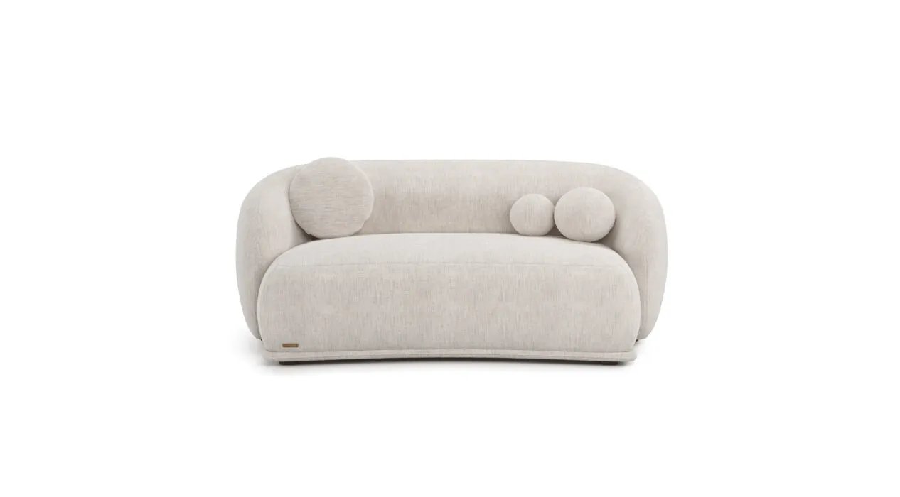 Kreminė Otis sofa iš priekio su lenktu atlošu ir trimis skirtingo dydžio apvaliomis pagalvėlėmis.