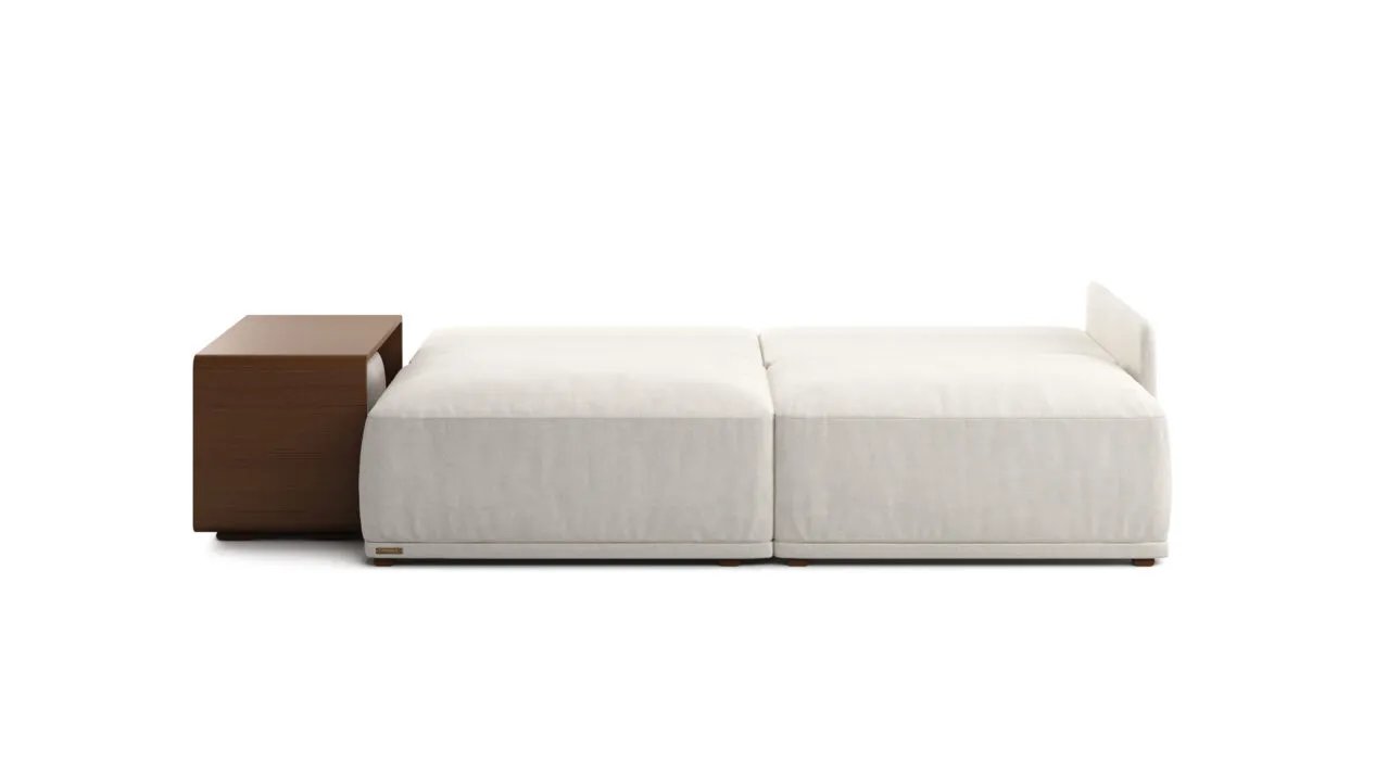 Iš šono matoma išskleista kreminė Cruse sofa lova su lygia miego dalimi ir rudos medžio apdailos staliuku.